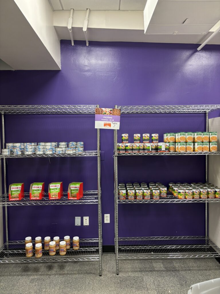 Photo of the proteins section of the pantry, including tuna, peanut butter, variety of beans. The shelves are halfway full. 